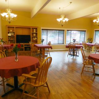 A spacious and inviting dining area with round tables, wooden chairs, and warm lighting.