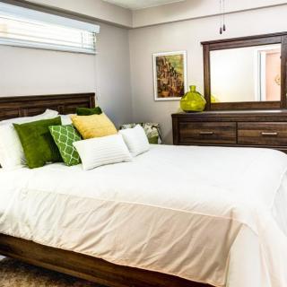 A modern bedroom with stylish wooden furniture and colorful pillows on a neatly made bed.