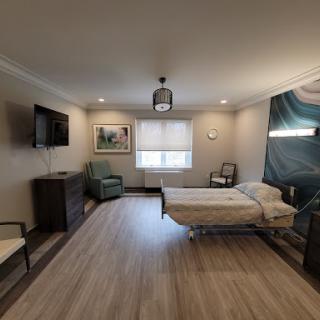 A well-lit and modern hospital patient room featuring a bed, TV, and seating area.
