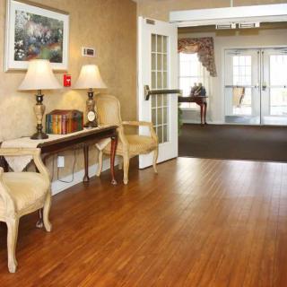 A cozy lobby area with chairs and a table adorned with lamps, leading to a bright doorway.