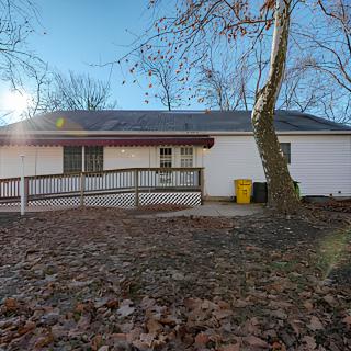 A house with a ramp in the backyard surrounded by trees and autumn leaves.