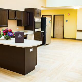 A modern kitchen with dark cabinets, stainless steel appliances, and a light countertop, adorned with a bouquet of flowers.