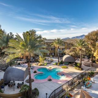 A scenic view of a resort featuring a unique flower-shaped swimming pool surrounded by palm trees and lounge areas.