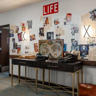 A vintage-themed setup featuring typewriters and a wall collage of retro magazine clippings, including a prominent Life Magazine sign.