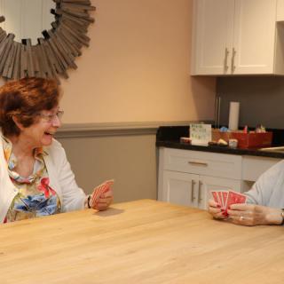 Two elderly women enjoying a game of cards in the kitchen.