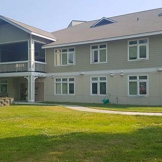 A two-story residential building with a green lawn in front.