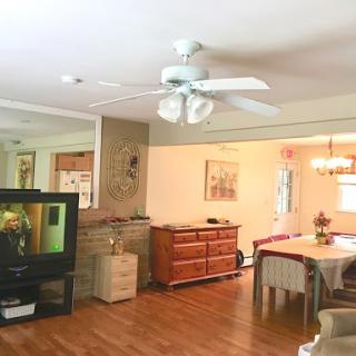 A cozy living room and dining area featuring a ceiling fan, television, and wooden furniture.