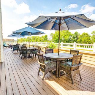 A sunny outdoor deck with tables, chairs, and umbrellas.