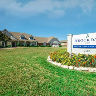 A building with a landscaped lawn and signage in front.