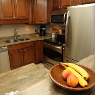 A cozy kitchen featuring wooden cabinets, modern appliances, and a bowl of fresh fruits.