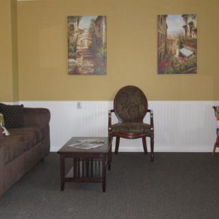 A cozy living room with a sofa, chair, coffee table, and wall art.