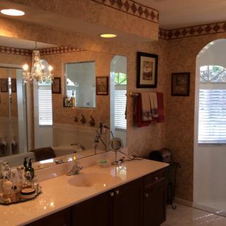 A well-decorated bathroom with a large mirror, chandelier, and neatly arranged towels.