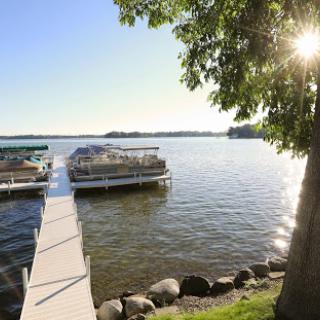A peaceful lakeside view with a dock reaching out into the calm waters, illuminated by soft sunlight.