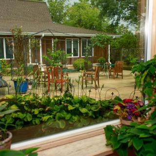 A view of a charming garden patio with chairs and lush greenery outside a house.