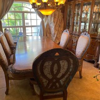 Elegant dining room with a large wooden table and upholstered chairs, illuminated by a chandelier.
