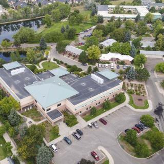 An aerial view of a building complex surrounded by trees and parking areas.