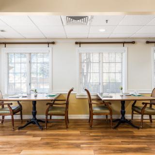 A cozy dining area with tables and chairs set by large windows.