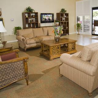 A cozy living room with comfortable sofas, a central wooden table, and decorative shelves.