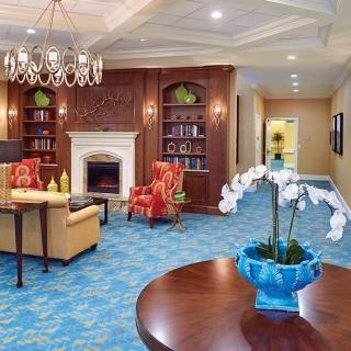 A cozy living room with a fireplace, elegant chandelier, and comfortable seating arrangements.