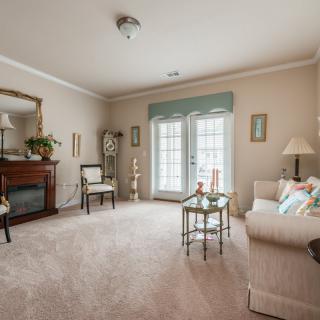 A cozy and traditionally decorated living room with a sofa, fireplace, and elegant furnishings.