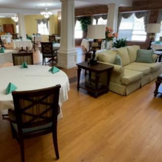 A cozy dining area with tables, chairs, and a sofa on hardwood flooring.