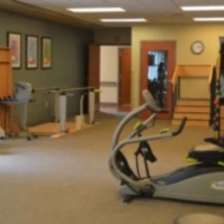 A gym with various exercise equipment and an open space for workouts.