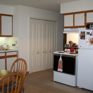 A cozy kitchen with a stove, dining table, and wooden cabinets.