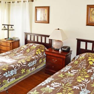A cozy bedroom featuring twin beds with floral patterned covers, wooden furniture, and framed art on the walls.