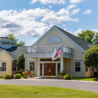 A picturesque building with a flag and well-maintained lawn under a cloudy sky.