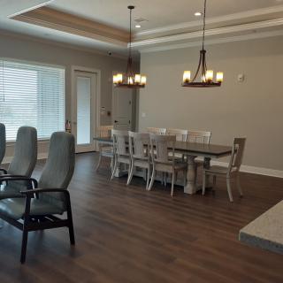 A modern dining room with a large table, elegant chandeliers, and hardwood flooring.