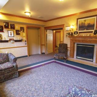 A cozy living room featuring a warm fireplace, comfortable seating, and decorative artwork.