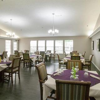 A well-lit dining area with neatly arranged tables and chairs, decorated elegantly.