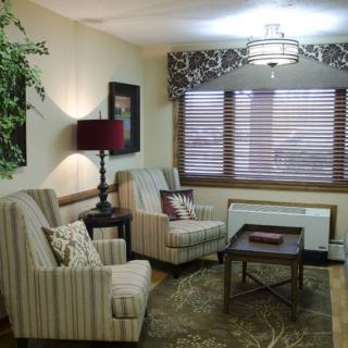 A cozy living room with striped armchairs, a coffee table, and decorative elements.