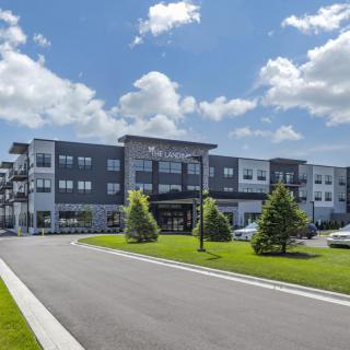 A modern apartment complex with well-maintained landscaping under a partly cloudy sky.