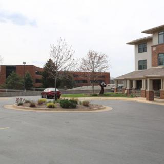 A view of a building with adjacent parking area and landscaping.