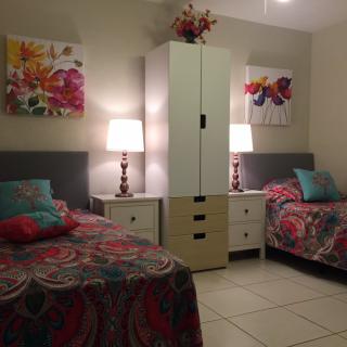 A cozy bedroom with twin beds adorned in colorful bedding and floral artwork.