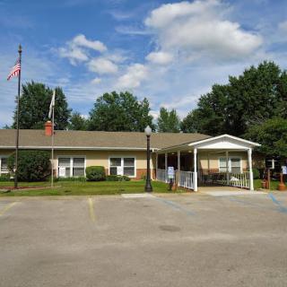 A welcoming community center surrounded by greenery and a clear blue sky.