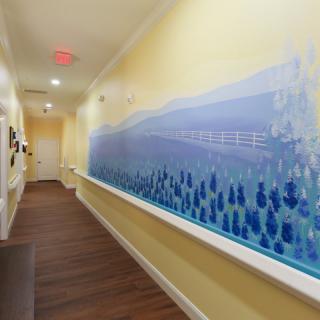 A well-lit hallway featuring a blue mural with wooden flooring.