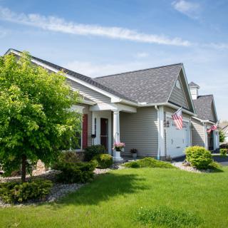 A suburban house with a well-maintained front lawn and an American flag displayed.