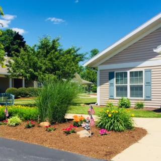 A well-maintained garden with colorful flowers and shrubs in front of a house.