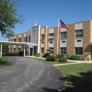 Exterior view of a hospital with an American flag, surrounded by greenery.