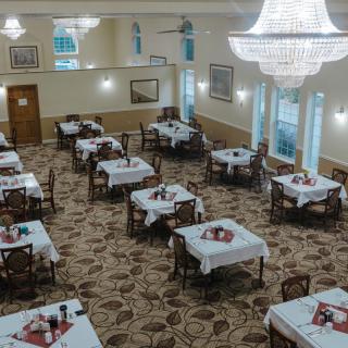 An elegantly decorated dining room with neatly arranged tables and chandeliers.