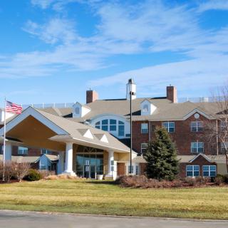 A large building with a prominent entrance and well-maintained grounds under a blue sky.
