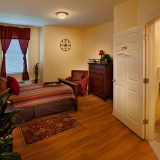 A cozy bedroom with elegant decor, featuring a comfortable bed, hardwood flooring, and warm lighting.