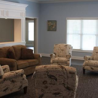 A cozy living room with a sofa and floral-patterned chairs arranged in a circle.