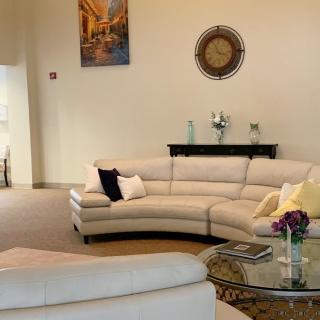 A stylish living room featuring a curved white sofa, decorative cushions, and wall art.