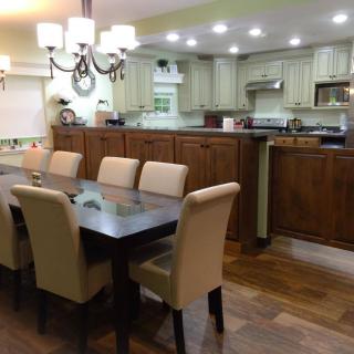 A modern dining area with a wooden table, upholstered chairs, and an adjacent kitchen.