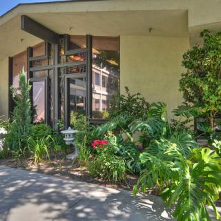 A modern house with a landscaped front yard featuring lush plants and foliage.