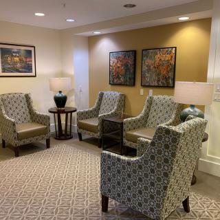 A cozy lobby area featuring patterned armchairs, artwork on the walls, and soft lighting.