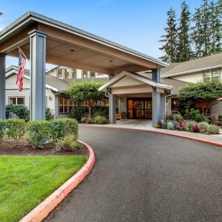 A welcoming building entrance with a covered driveway and landscaped surroundings.